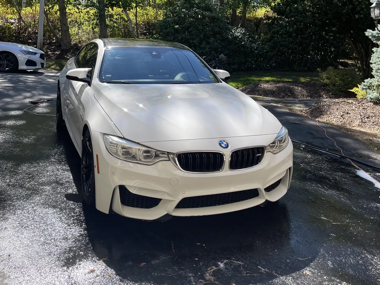 A white BMW M4 on a wet driveway